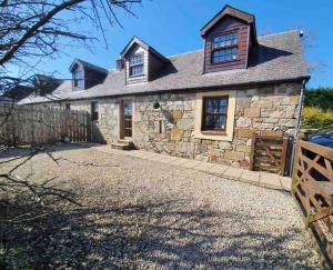 a stone house with a fence in front of it at Baidland Escapes 2 bedroom cottage With hot tub in Dalry