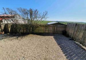 a fence in front of a yard with a tree at Baidland Escapes 2 bedroom cottage With hot tub in Dalry