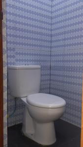 um WC branco numa casa de banho com uma parede azul em Taras Homestay em Seribu