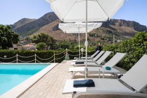 a row of lounge chairs with an umbrella next to a swimming pool at VFH Villa Flavia Eco B&B - 50 metri dal mare in Santa Flavia