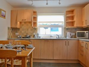 cocina con armarios de madera, mesa y ventana en Elens Place, en Tywyn