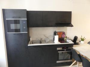 uma cozinha com armários pretos e um lavatório em Superbe Maison Rénovée en Centre-ville em Saint-Pierre-dʼOléron