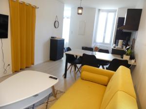 a living room with a yellow couch and a table at Superbe Maison Rénovée en Centre-ville in Saint-Pierre-dʼOléron