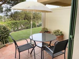 eine Terrasse mit einem Tisch, Stühlen und einem Sonnenschirm in der Unterkunft Villa Romuald in Sainte-Maxime