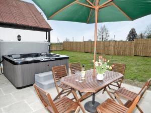 a picnic table with an umbrella and a barbecue at Beacon Cottage - E5463 in Wainfleet All Saints