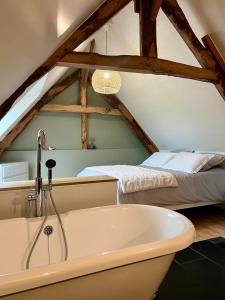 ein Badezimmer mit einer Badewanne neben einem Bett in der Unterkunft Le Clos des écureuils in Audrieu