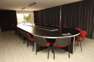 a conference room with a black table and red chairs at Aventus Hotel in Akhaltsikhe