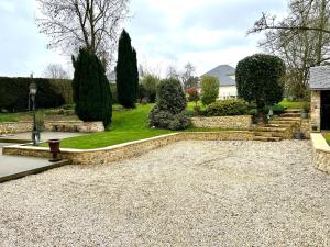 einen Garten mit einem Steinpfad sowie Bäumen und Sträuchern in der Unterkunft Le Clos des écureuils in Audrieu