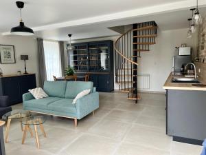 ein Wohnzimmer mit einem blauen Sofa und einer Küche in der Unterkunft Le Clos des écureuils in Audrieu