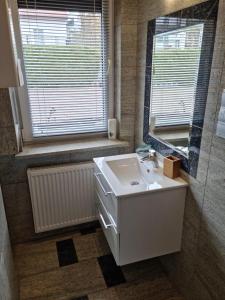 a bathroom with a white sink and a mirror at Apartament BURSZTYNEK in Pobierowo