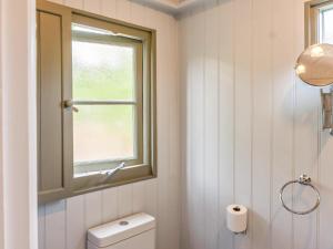 a white bathroom with a window and a toilet at Fig Tree Shepherds Hut in Bridport