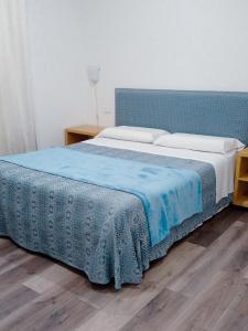 een slaapkamer met een bed met een blauw hoofdeinde bij Gemini camere e suites in Grosseto