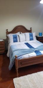 a bed with a blue and white blanket and pillows at Casa da Ribeira in Povoação