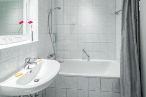 a white bathroom with a sink and a tub at Top Appartements Roth am Strande in Westerland (Sylt)