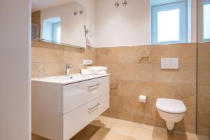 ein Badezimmer mit einem weißen Waschbecken und einem WC in der Unterkunft Hotel Gasthof Sonnenhang in Denkendorf
