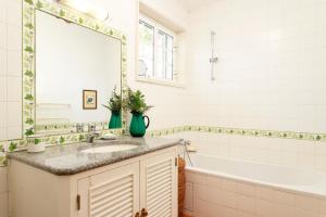 a bathroom with a sink and a tub and a mirror at Vila Chácara Flora em Malveira da Serra in Alcabideche +24 photos