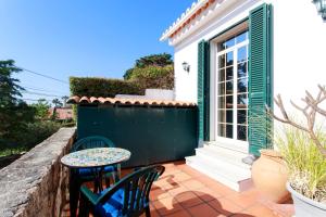 a patio with two chairs and a table and a window at Vila Chácara Flora em Malveira da Serra in Alcabideche