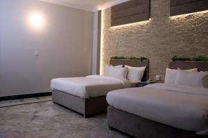 a hotel room with two beds and a brick wall at Hayat Grand Guest House Islamabad in Islamabad