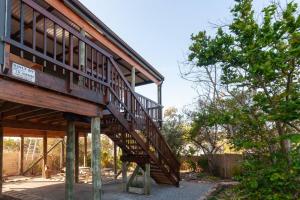 a wooden house with a staircase next to a tree at The Whalehouse in Wilderness