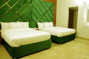 2 camas en una habitación de hotel con 2 colchas en Hayat Grand Guest House, en Islamabad