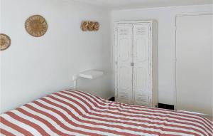 1 Bedroom Beautiful Apartment In Cucq في كوسيك: غرفة نوم بيضاء مع سرير مخطط وخزانة