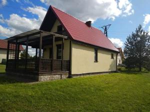 a house with a red roof on a green field at Domki Orla na Mazurach in Pasym