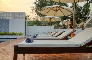 szereg leżaków z parasolami na patio w obiekcie Chic stay HANA Boutique hotel w mieście Luang Prabang