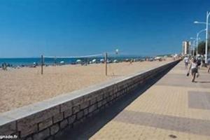 un mur de retenue à côté d'une plage où les gens marchent dans l'établissement Maison de vacances bord de mer, idéal famille ou groupe 8 pers, à Sérignan