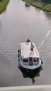 a person standing on a boat in the water at Zouw Hausboat Zakotven -pouze ubytovaní in Roudnice nad Labem