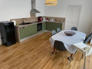 eine Küche mit einem Tisch und eine Küche mit grünen Schränken in der Unterkunft Appt 130m2-Jusqu'à 3 Chambres-Centre ville-Moulins-Le Pal in Moulins