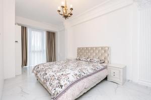 a white bedroom with a bed and a chandelier at Main Street Sky House Apartments in Chişinău