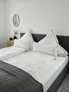 Una cama con sábanas blancas y almohadas. en Weinstadt Monteurwohnnung Ferienwohnung, en Weinstadt