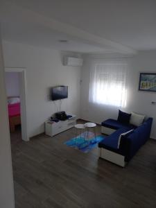 uma sala de estar com um sofá azul e uma televisão em Apartman Jass em Stari Banovci