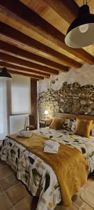 ein Schlafzimmer mit einem großen Bett und einer Steinmauer in der Unterkunft L'Urdet in San Lorenzo de Morunys