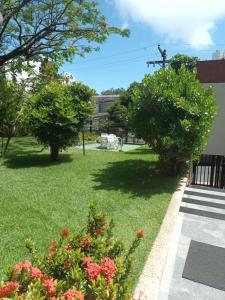a yard with two trees and grass and flowers at Barra Summer Flat Apart in Salvador