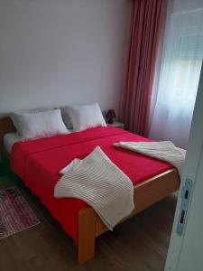 um quarto com uma cama com um cobertor vermelho em Apartman Jass em Stari Banovci
