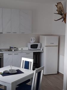 uma cozinha com uma mesa e um frigorífico branco em Apartman Jass em Stari Banovci