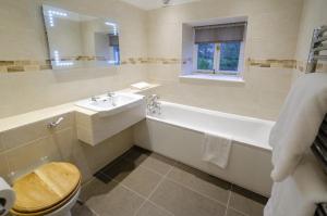 Baño blanco con bañera y lavamanos en Skelwith Fold Cottage No.1 en Elterwater