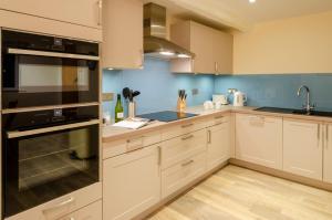 a kitchen with white cabinets and black appliances at Skelwith Fold Cottage No.1 in Elterwater