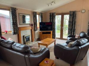 a living room with leather couches and a television at Getaway Lodge in Ilfracombe