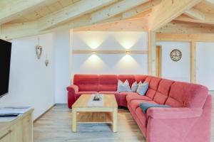 a red couch in a living room with a table at Ferienwohnung Partnachklamm in Garmisch-Partenkirchen
