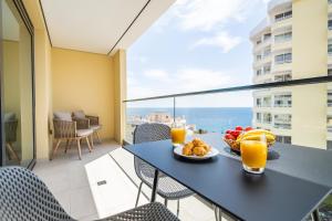 - une table avec une assiette de nourriture et de jus d'orange sur un balcon dans l'établissement Apartment with ocean view and parking, à Funchal