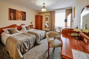a hotel room with two beds and a desk at Biały Dom Henlex Hotel Restauracja in Poznań