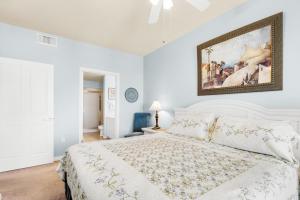 a white bedroom with a white bed and a painting on the wall at Destin West Gulfside #608 in Fort Walton Beach