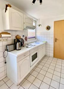 a kitchen with white cabinets and a white tiled floor at Ferienwohnung Peters in Trebel