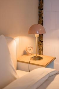 a bedside table with a lamp and a clock on it at St.Jacobs's apartments Old Town Riga in Rīga