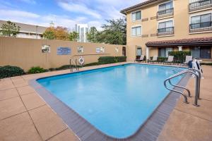 une grande piscine en face d'un bâtiment dans l'établissement Courtyard by Marriott Houston Rice University, à Houston