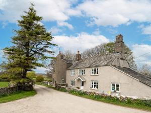 an old house with a tree on the side of a road at Longlands Farm Cottage in Grange Over Sands