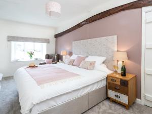 a bedroom with a large white bed and a window at Longlands Farm Cottage in Grange Over Sands