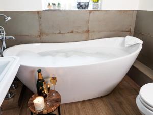a white bath tub in a bathroom with champagne glasses at Longlands Farm Cottage in Grange Over Sands +67 photos